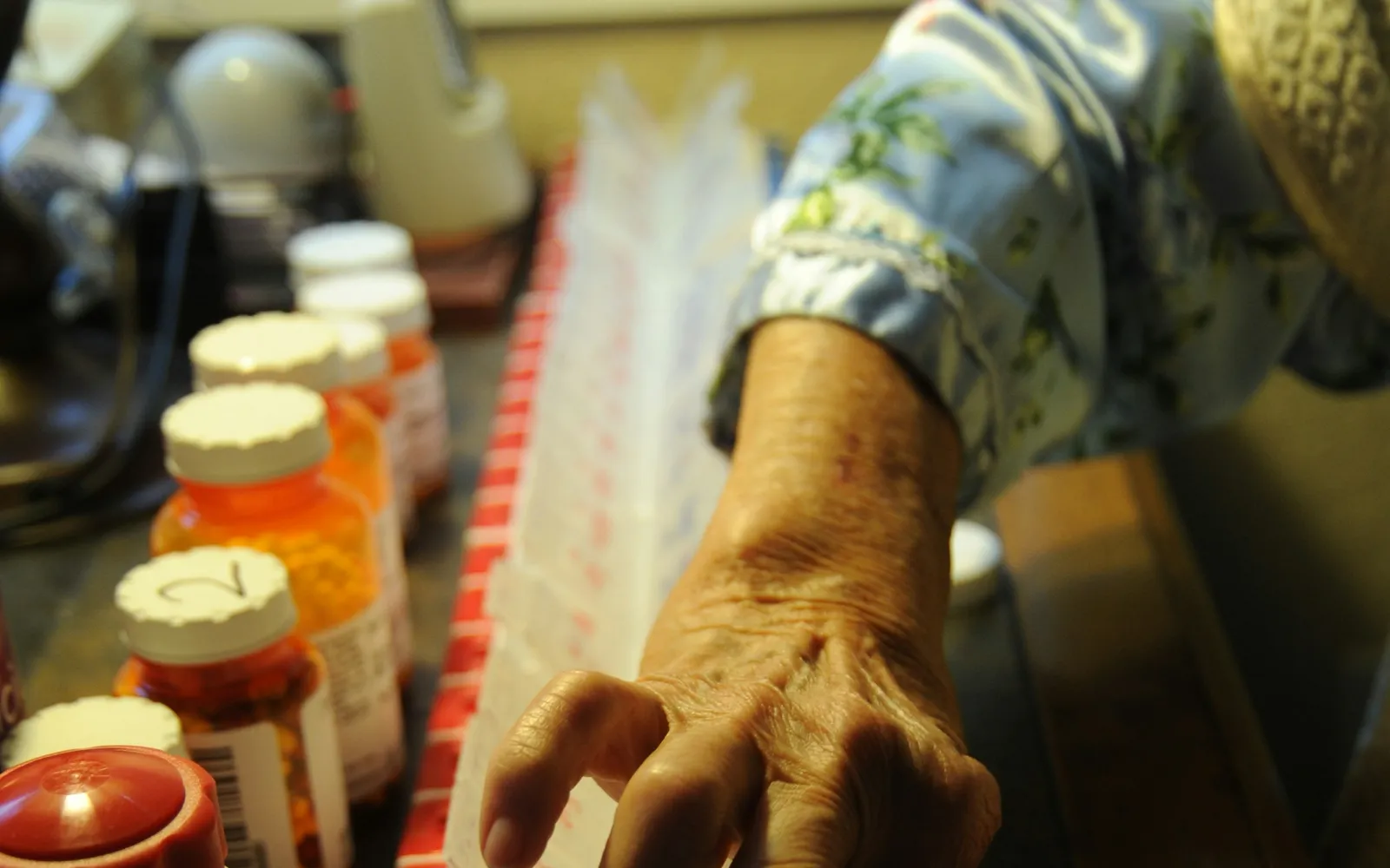 An older person's hands sorting pills into a monthly pill organizer