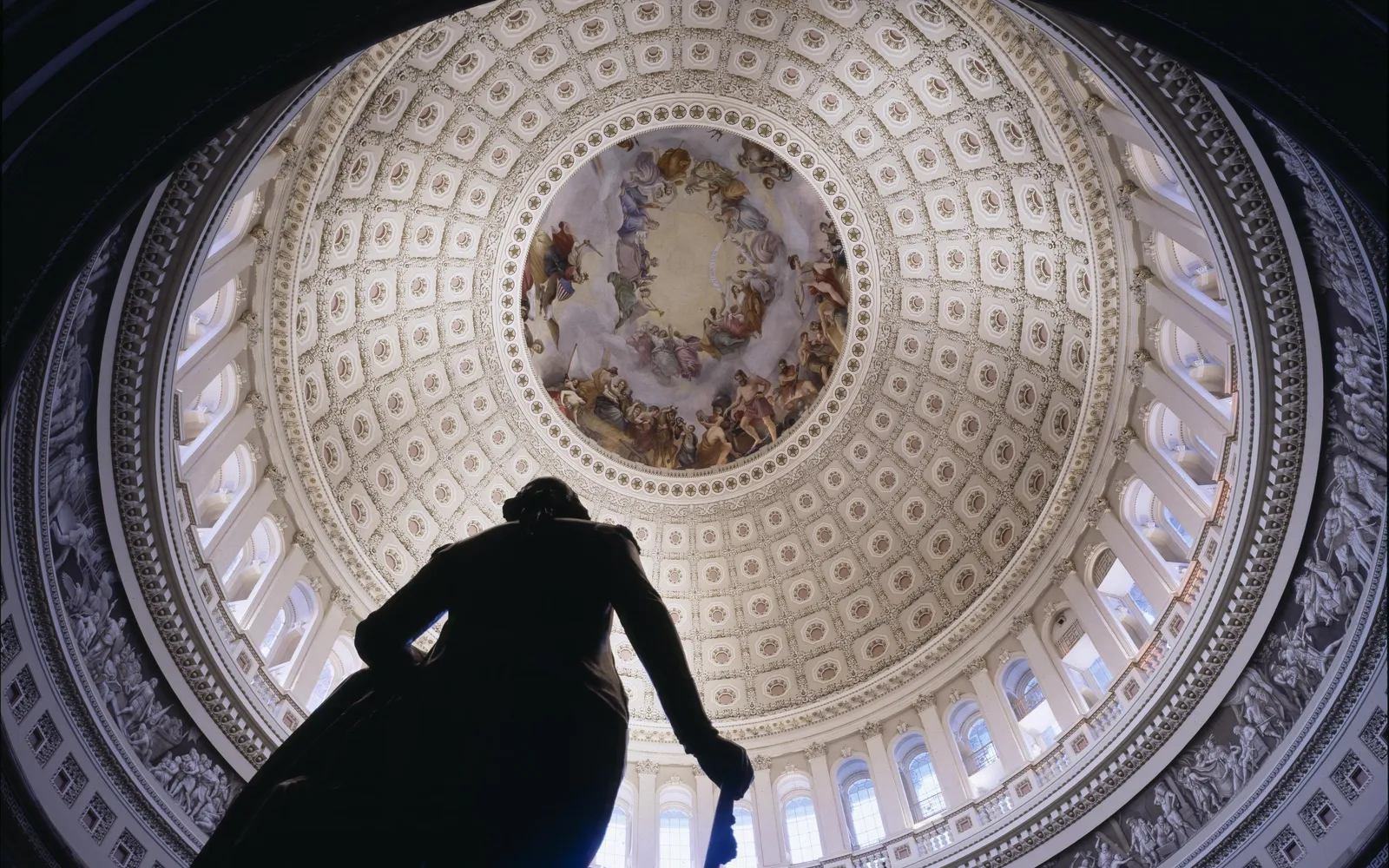 Looking up into the U.S. Capitol dome, a statue silhouetted against the coffered ceiling