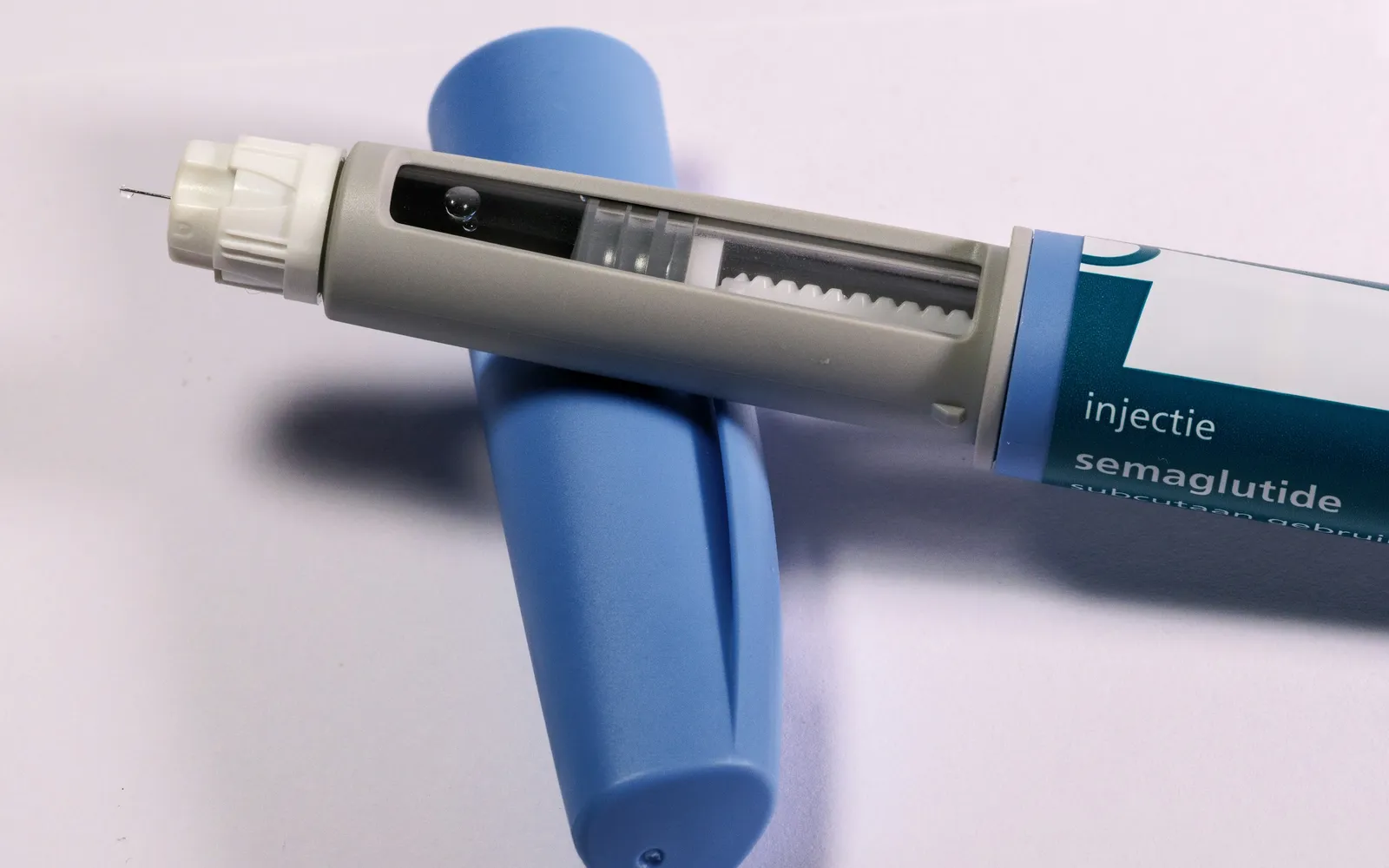 A blue semaglutide injection pen with its cap on a light background