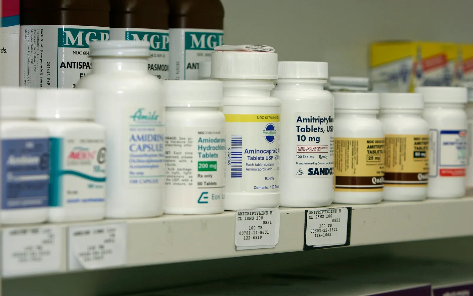 Rows of white prescription bottles on a pharmacy shelf