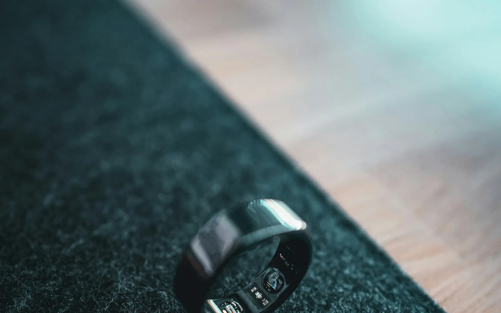 A dark smart ring resting on a green textured surface